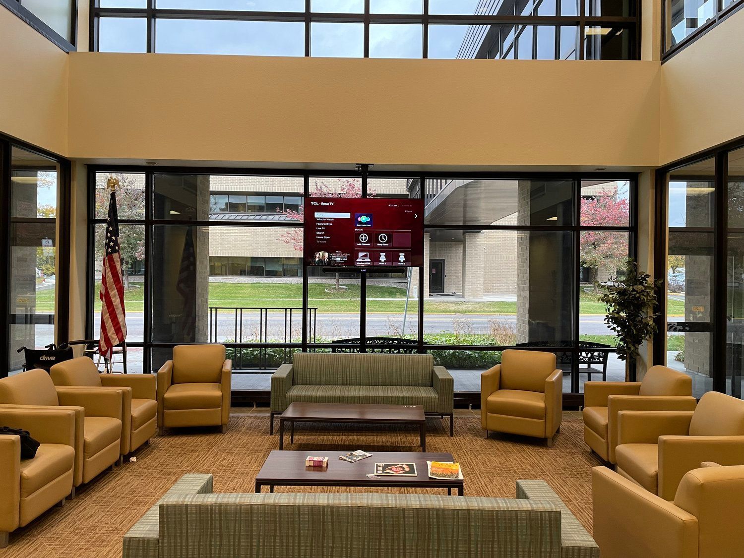 A living room with a couch , chairs , and a television on the wall.