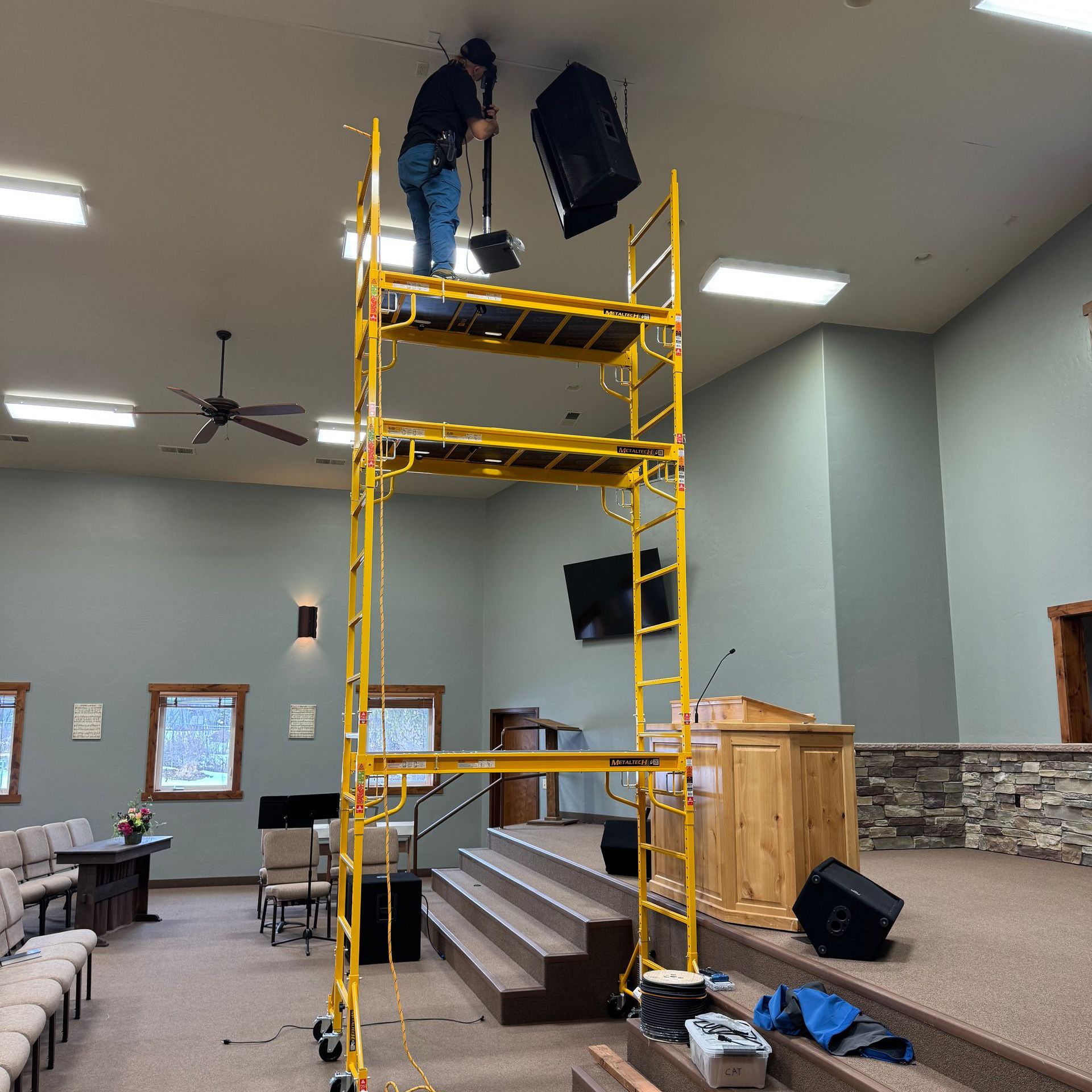 A man is standing on a yellow scaffolding in a room