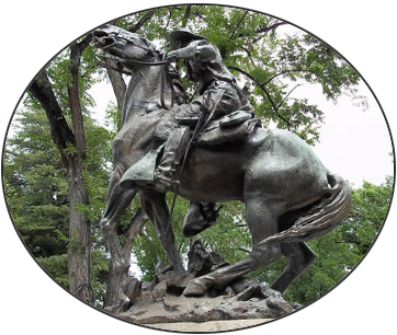 A statue of a man riding a horse with trees in the background