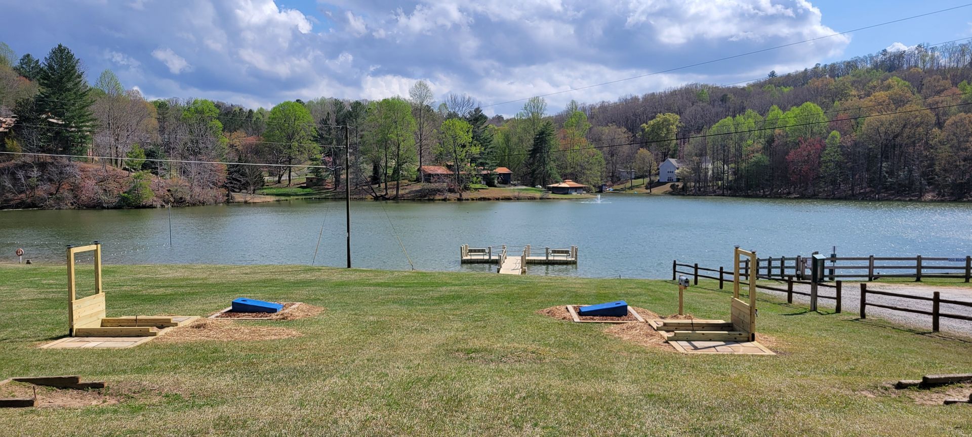 A lake with a fence in the foreground and trees in the background