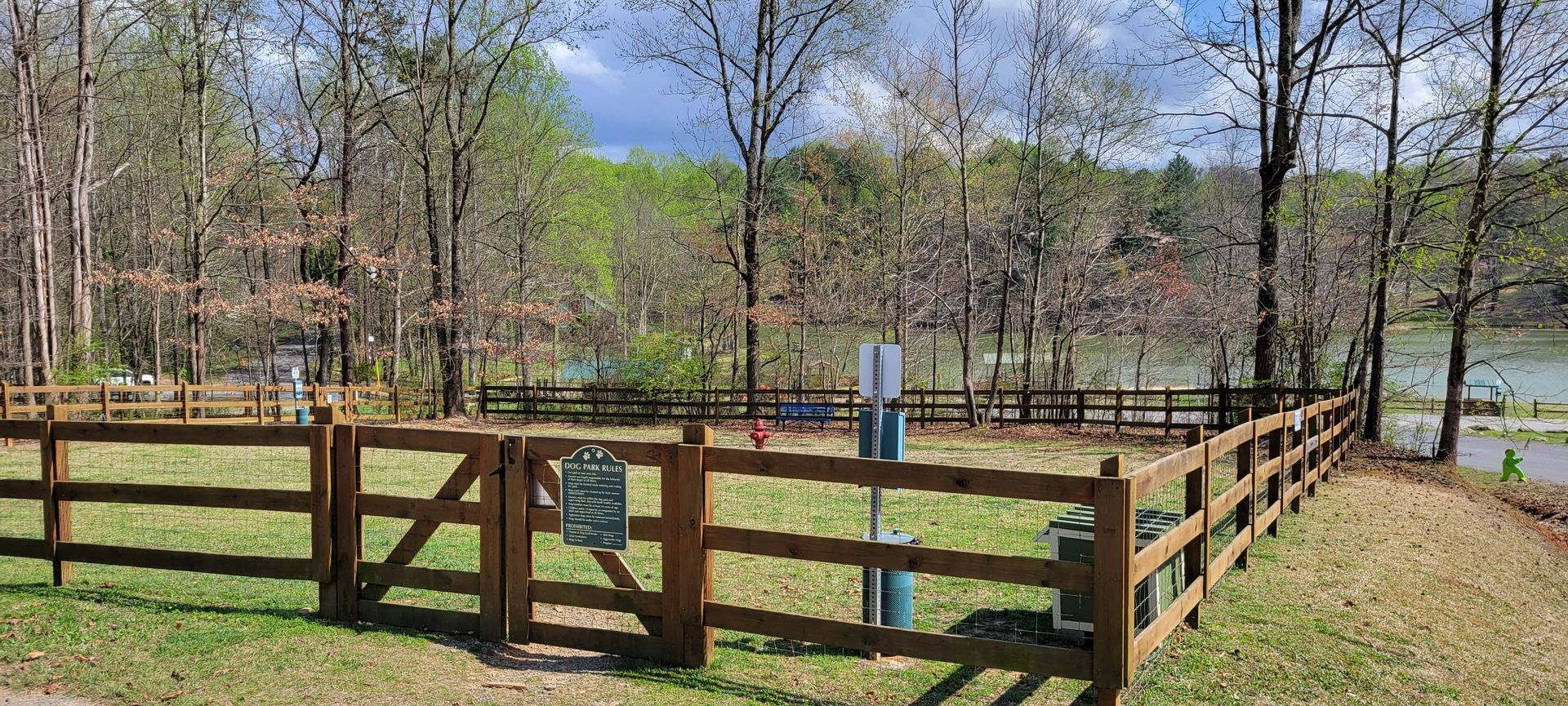 A wooden fence surrounds a grassy area with trees in the background.