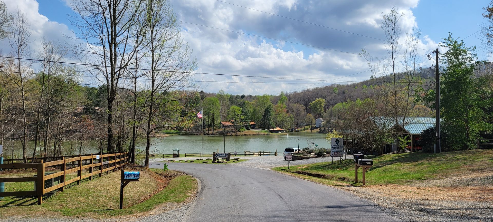 A dirt road leads to a lake surrounded by trees