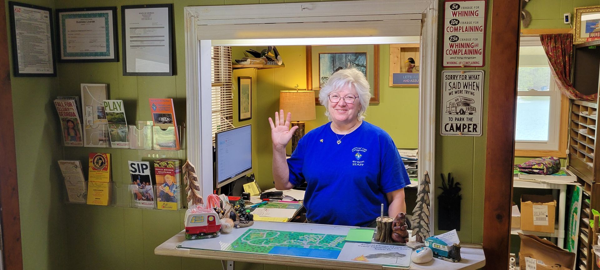 A woman in a blue shirt is waving at the camera