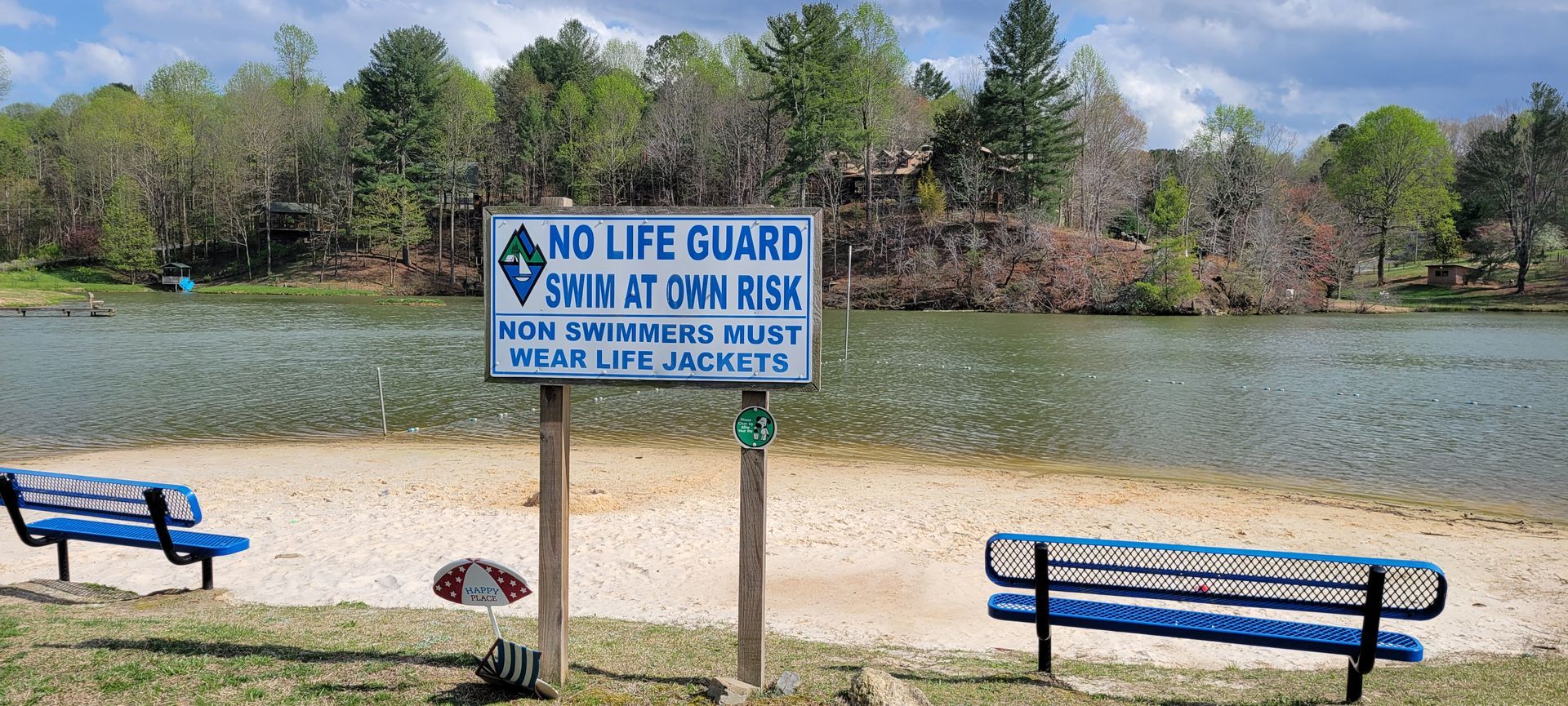 A no life guard sign is in front of a lake