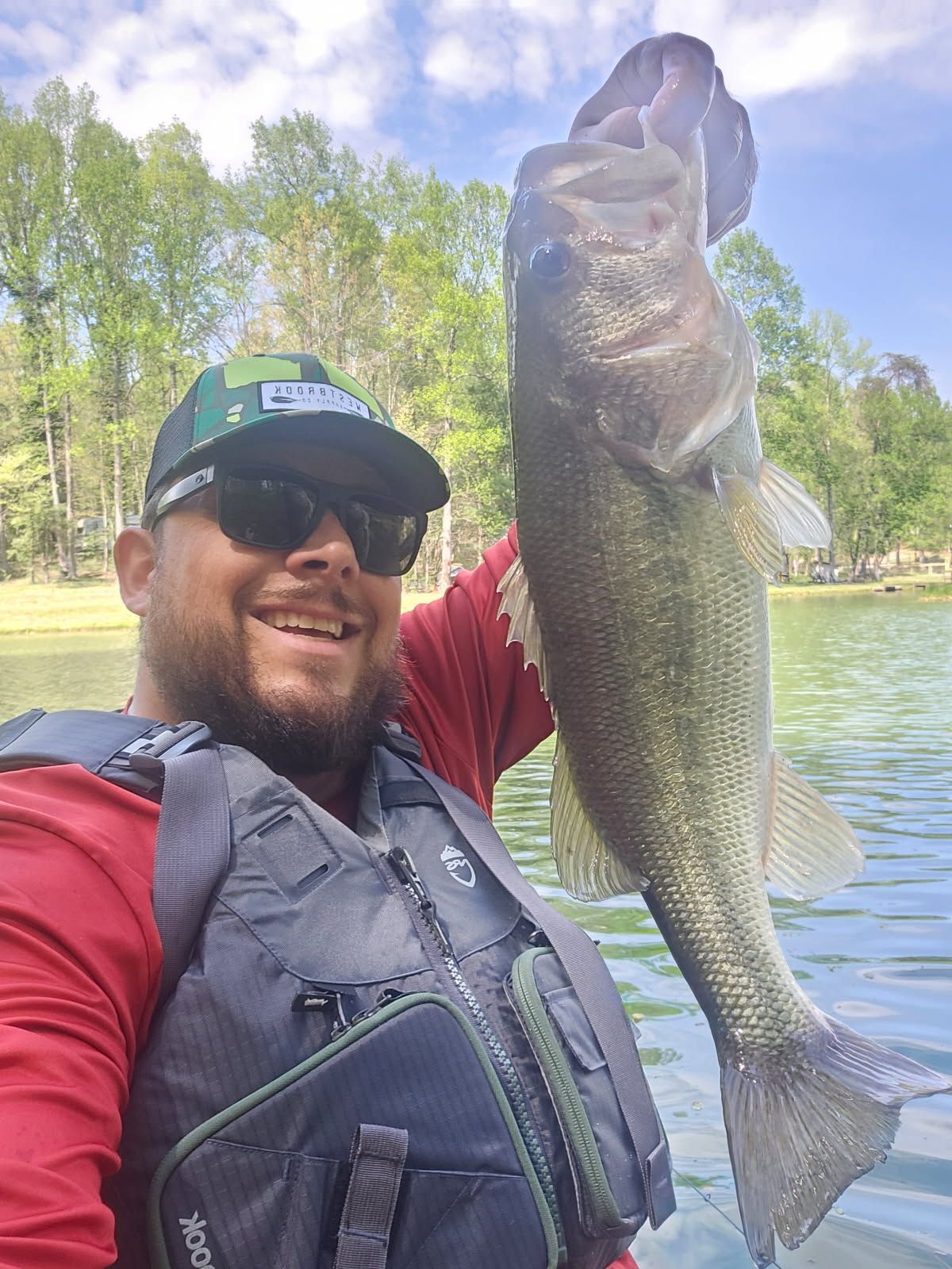 A man in a life jacket is holding a large fish in his hands.