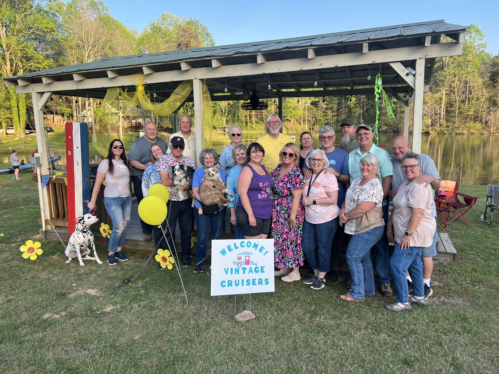 A group of people standing in front of a sign that says Welcome vintage cruisers