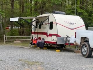 A trailer is parked next to a truck in a gravel lot.