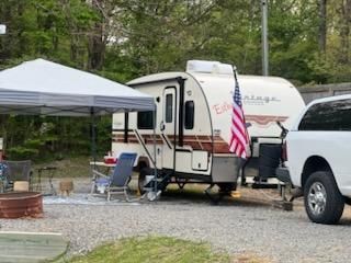 A rv is parked in a gravel lot next to a white van.