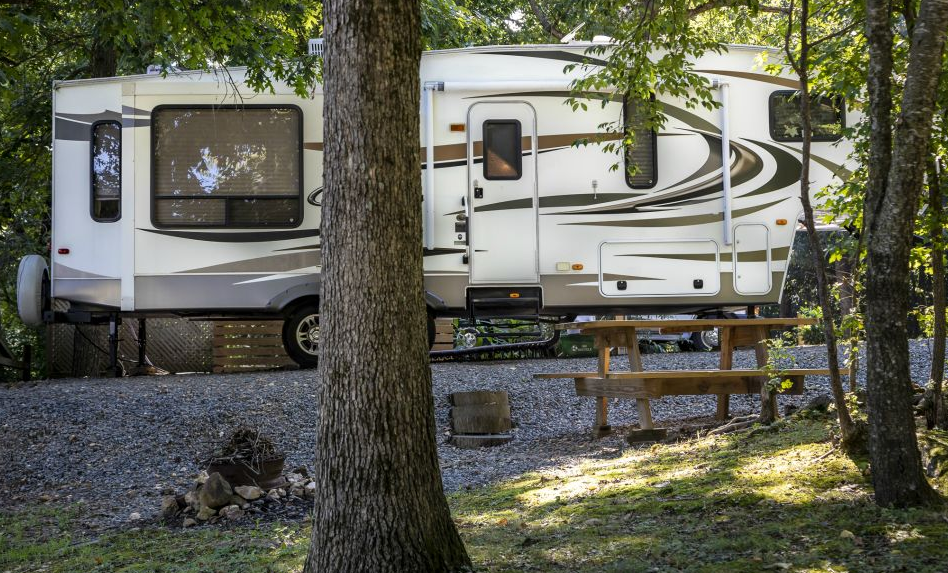 A rv parked in the woods with a picnic table