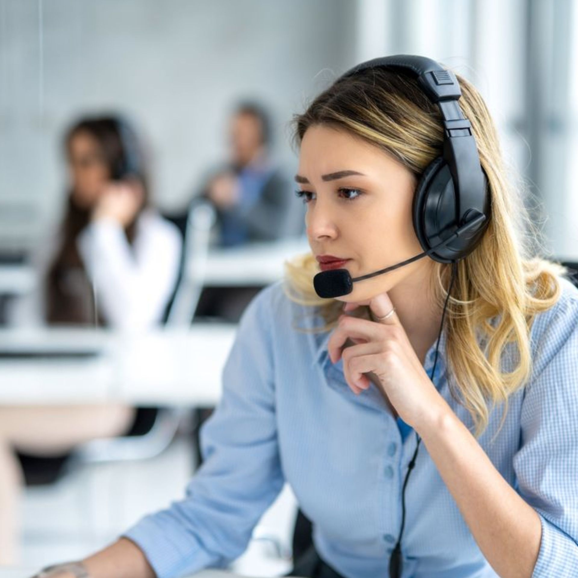 Call center agent wearing a headset, speaking attentively in an office