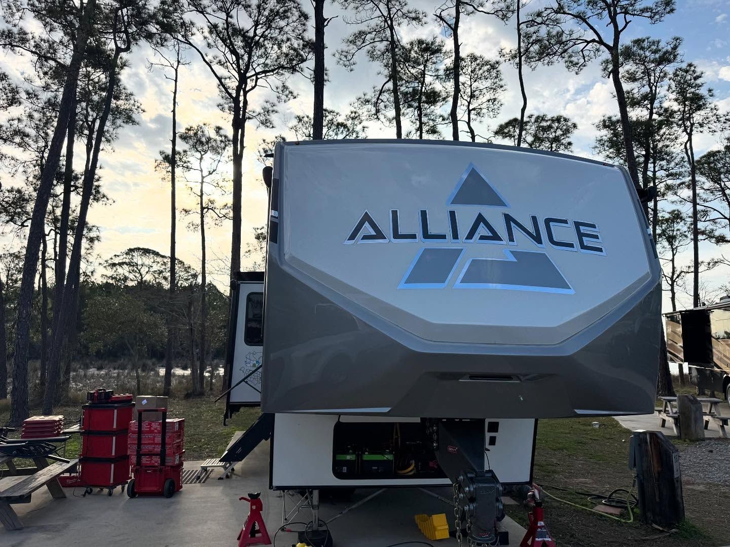 A rv with the word alliance on the side is parked in a forest.