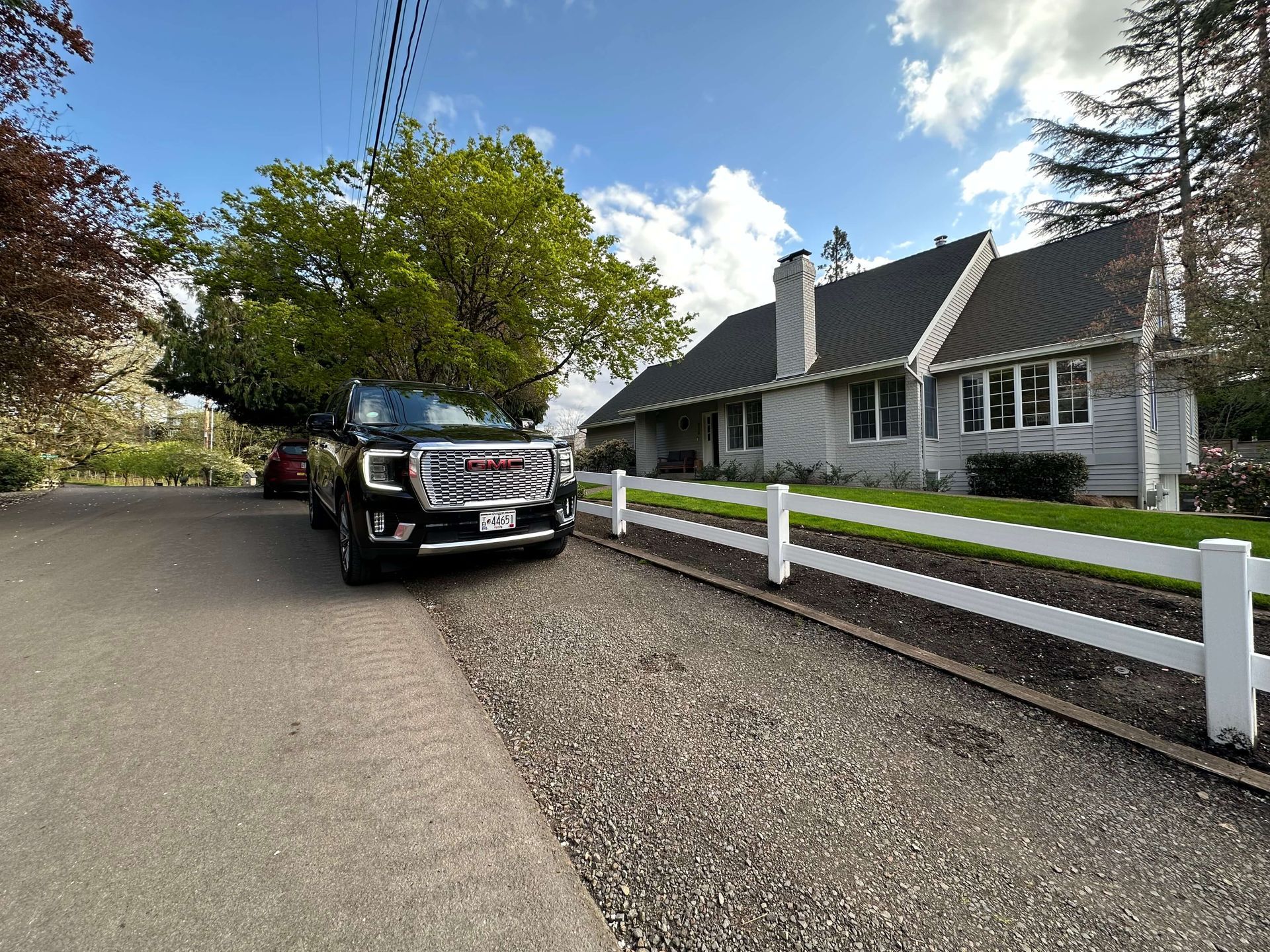 A car is parked in front of a house with a white fence in lake oswego oregon