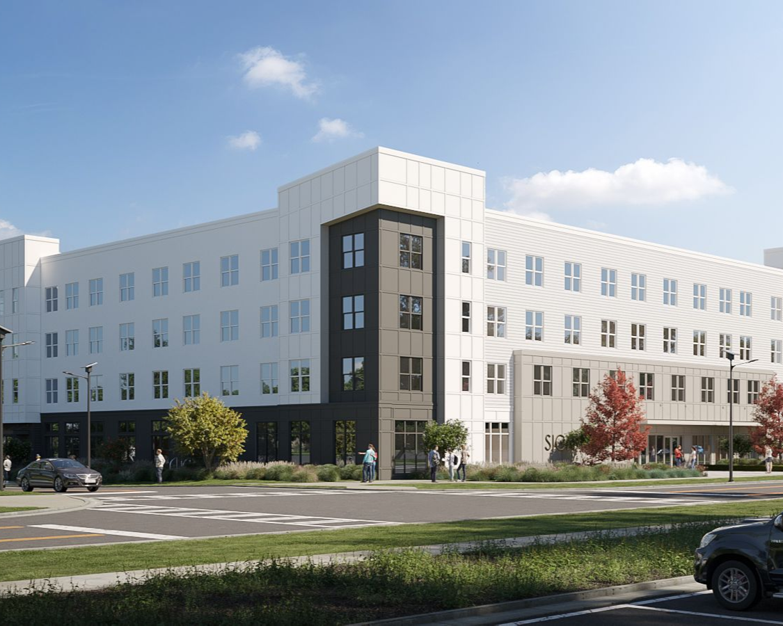 Modern multi-story building with white and dark grey exterior, people and cars visible.