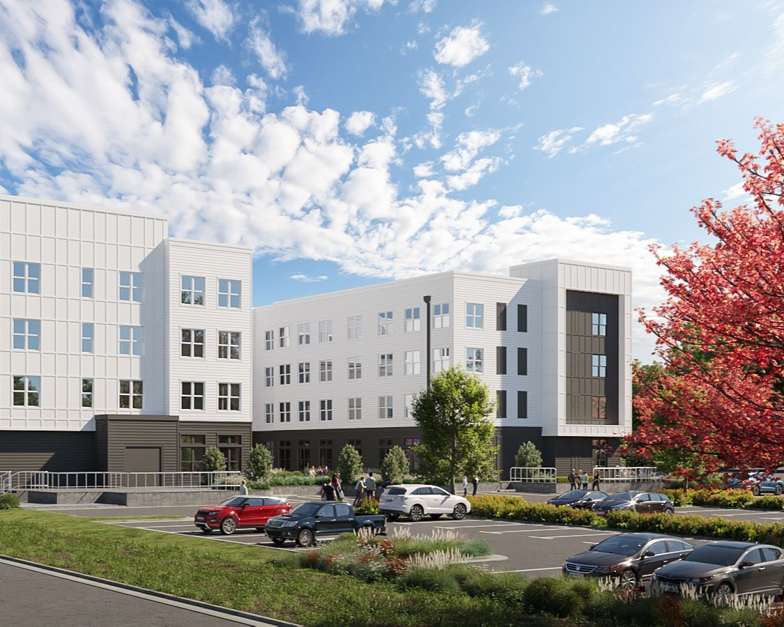 Modern multi-story apartment building with parked cars, landscaping, and a blue sky.