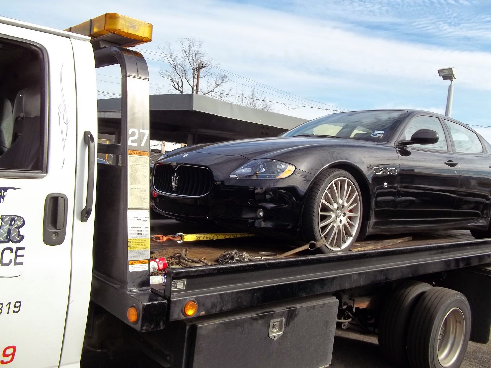 Black maserati sedan loaded on a tow truck's flatbed