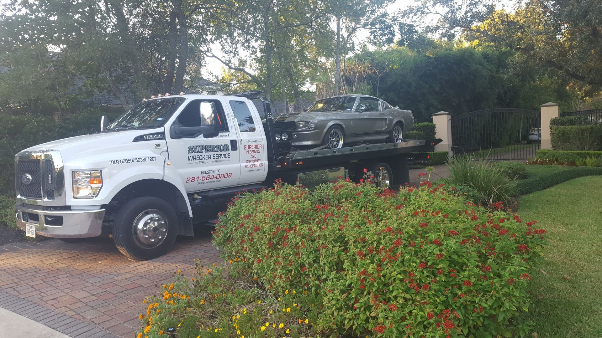 Tow truck with a classic grey car parked on a driveway