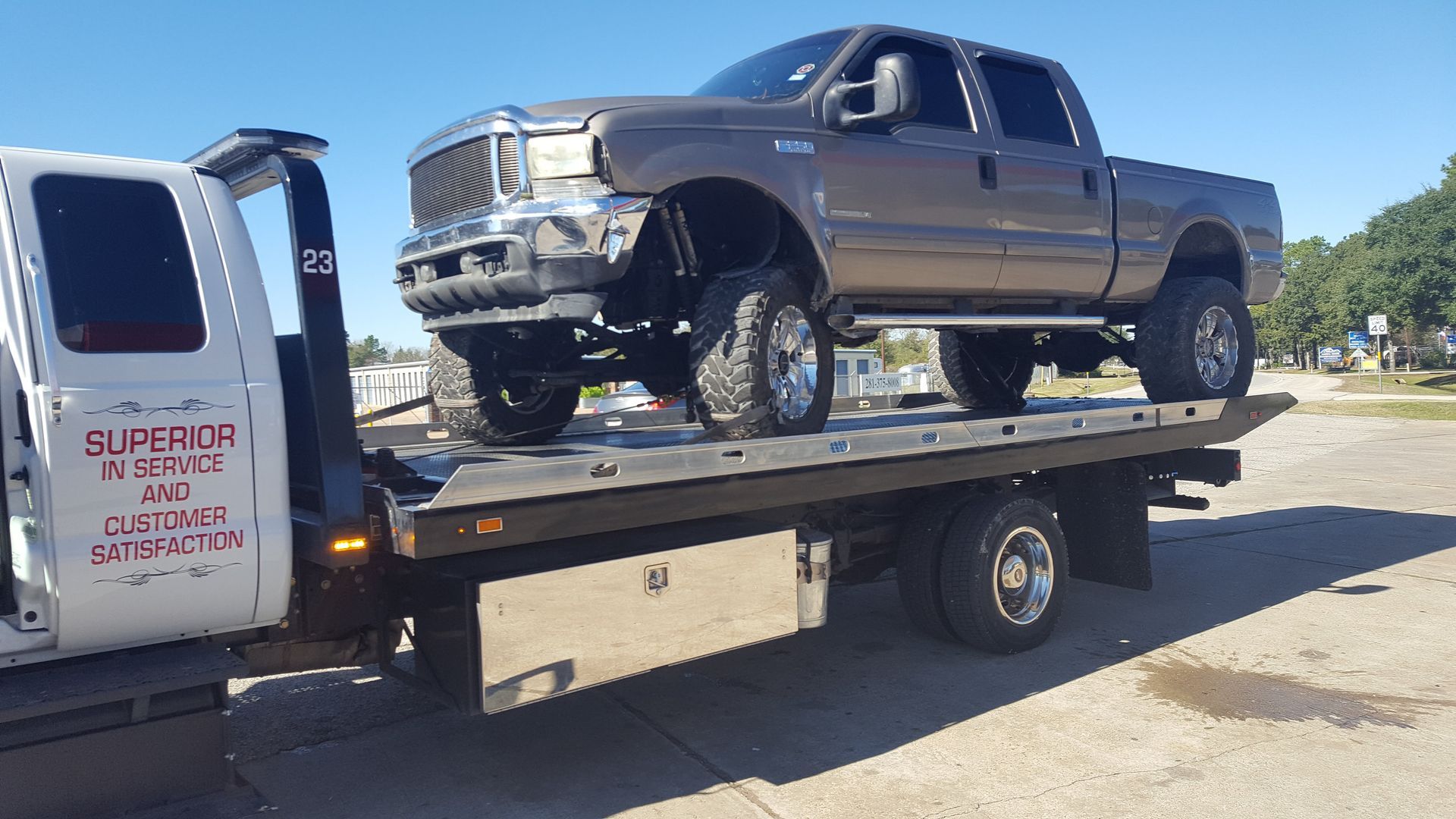A brown pickup truck being transported on the flatbed