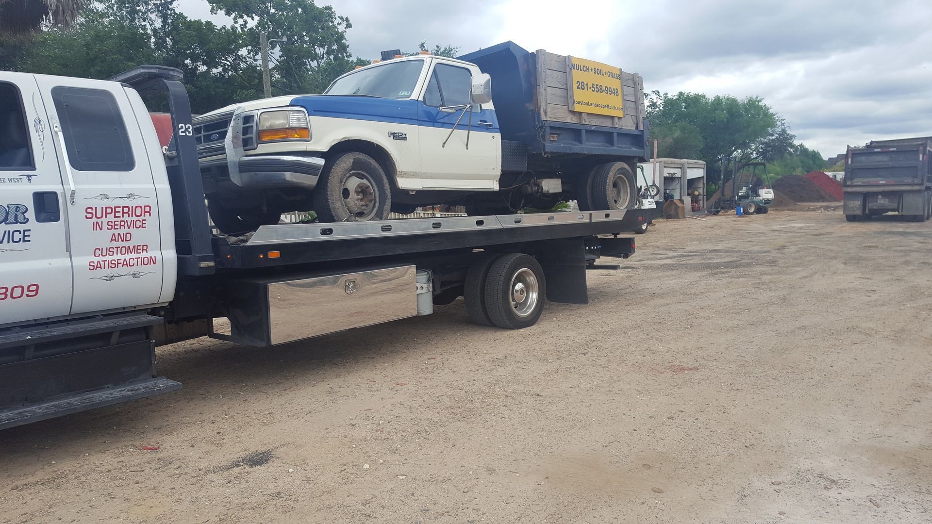 Tow truck carrying a white and blue pickup truck