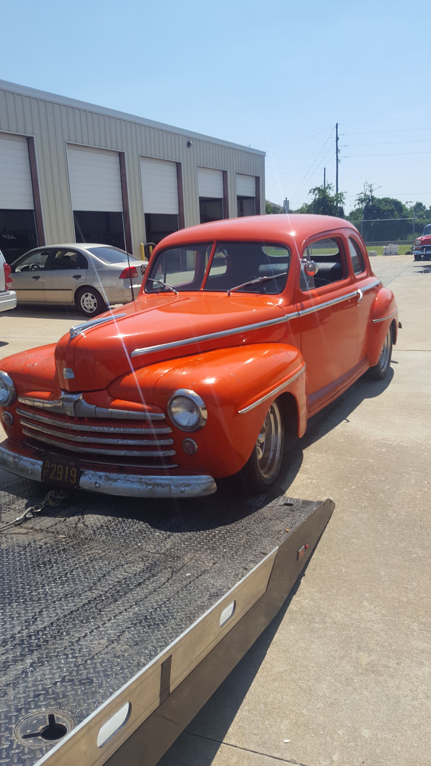 Orange vintage car on a flatbed tow truck