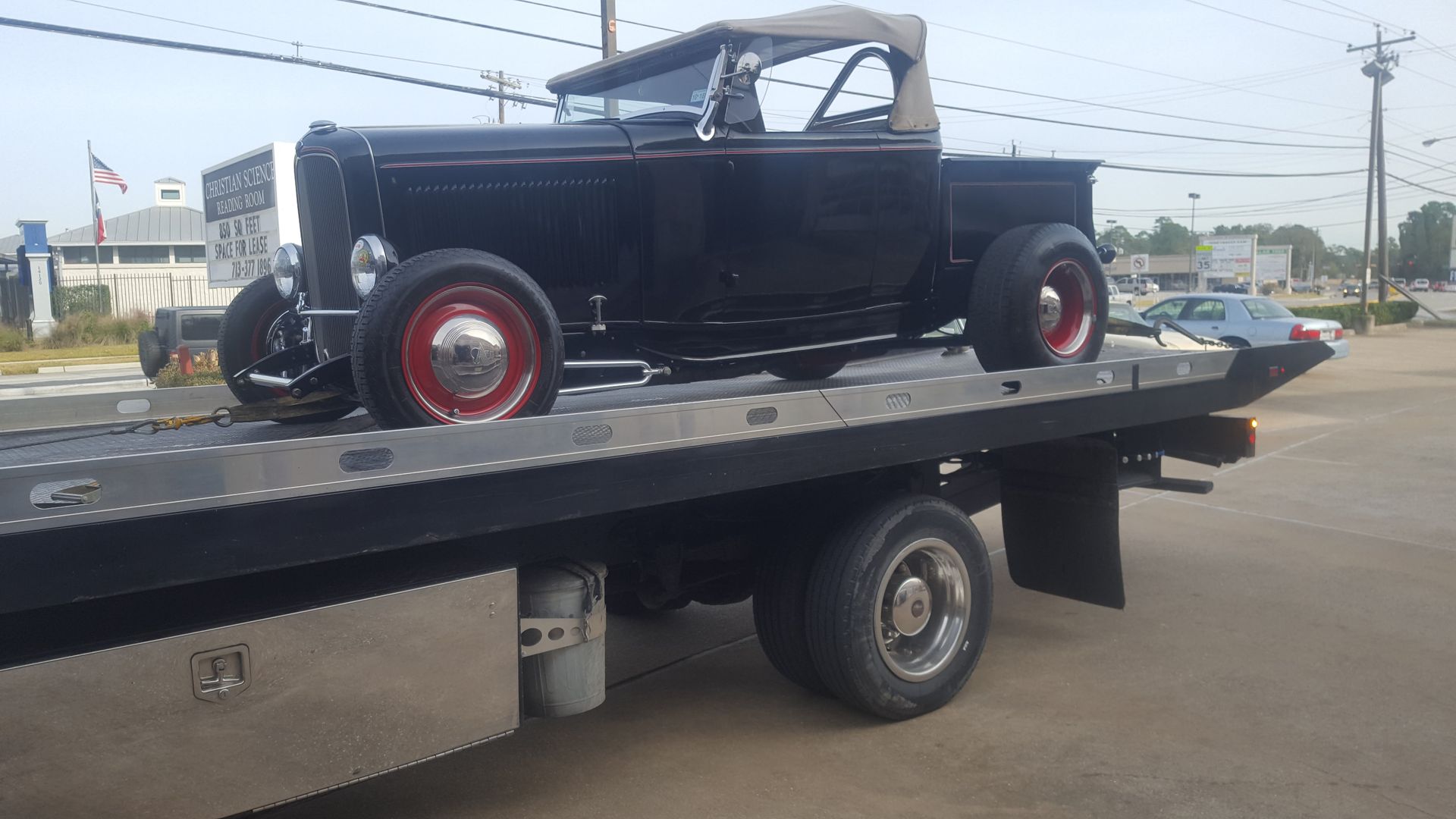 Black classic pickup truck with red wheels on a tow truck