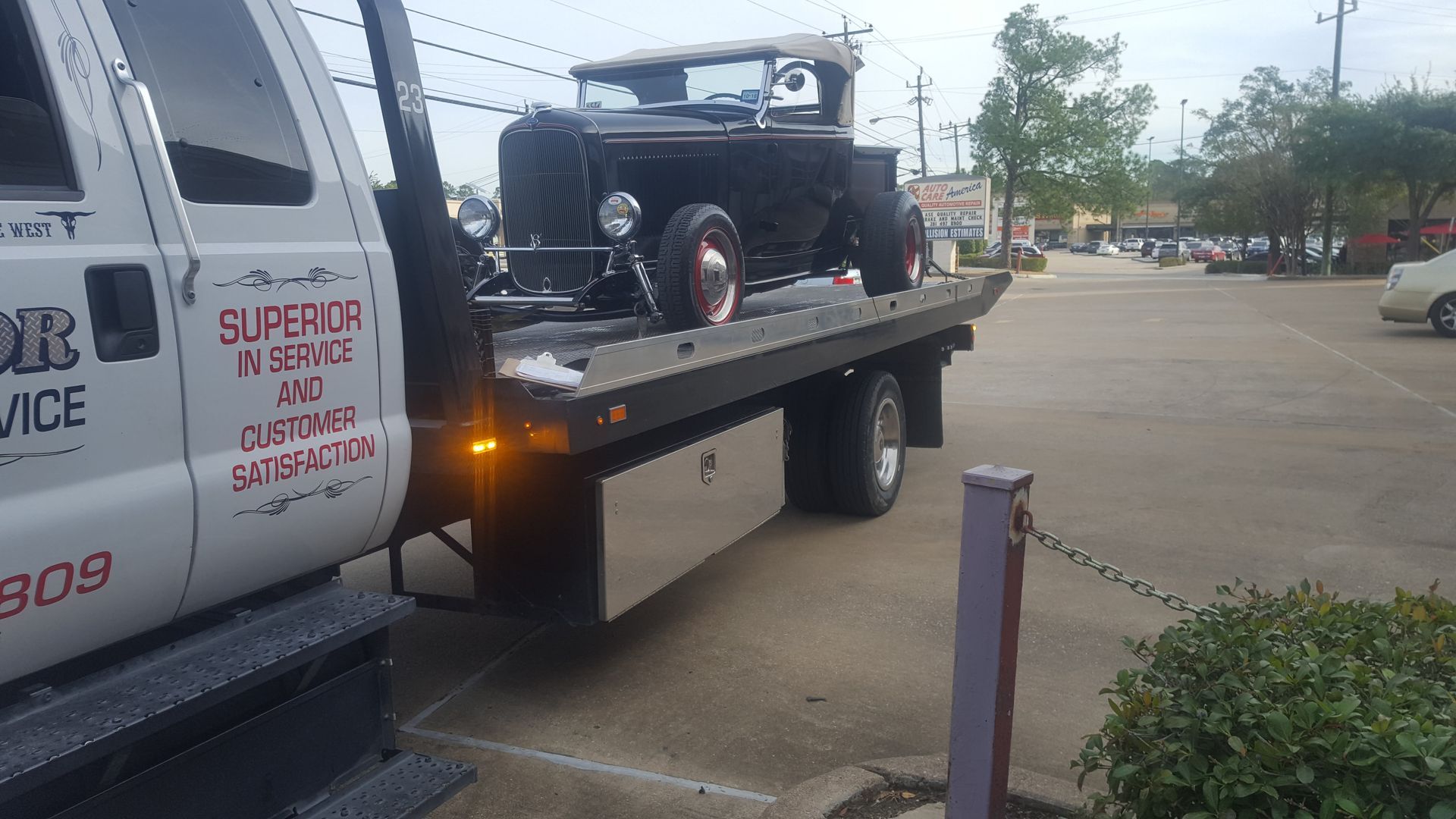 Black antique car on a flatbed tow truck