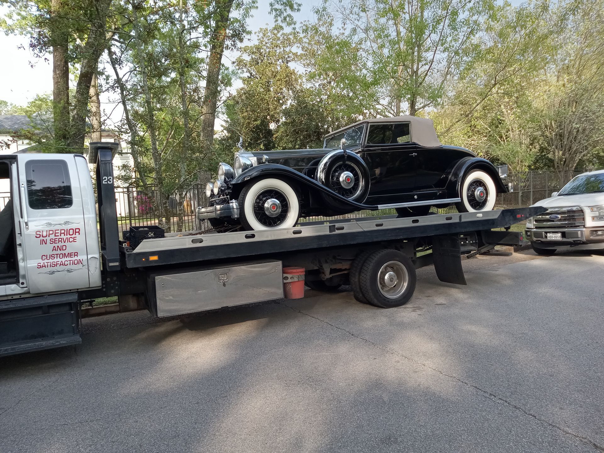 Black vintage car on a flatbed tow truck on a street