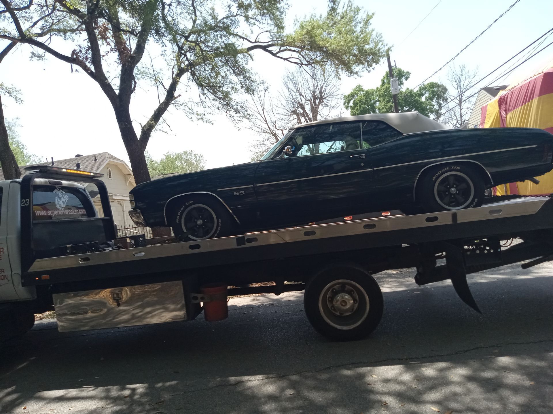 Dark green classic convertible car on a flatbed tow truck