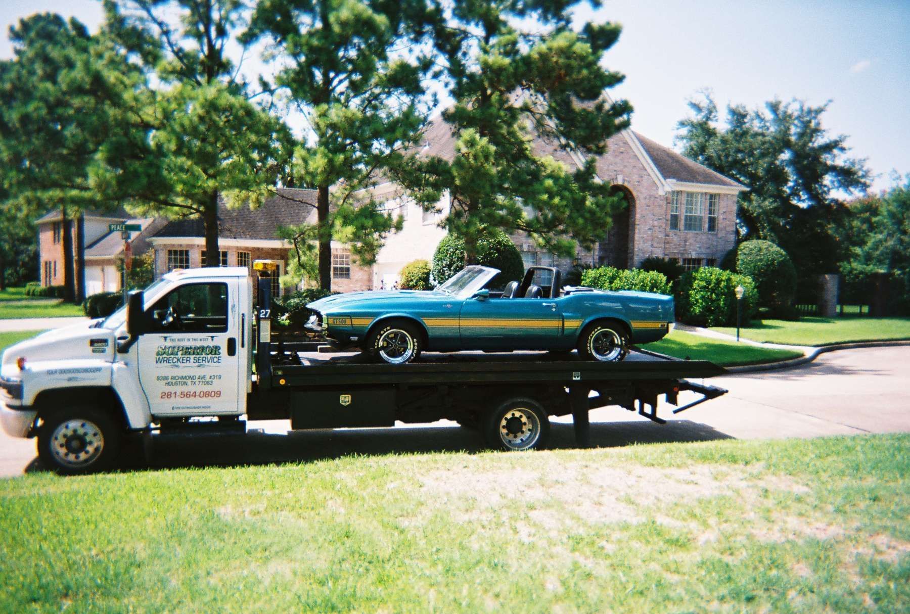 Tow truck carrying a turquoise convertible car