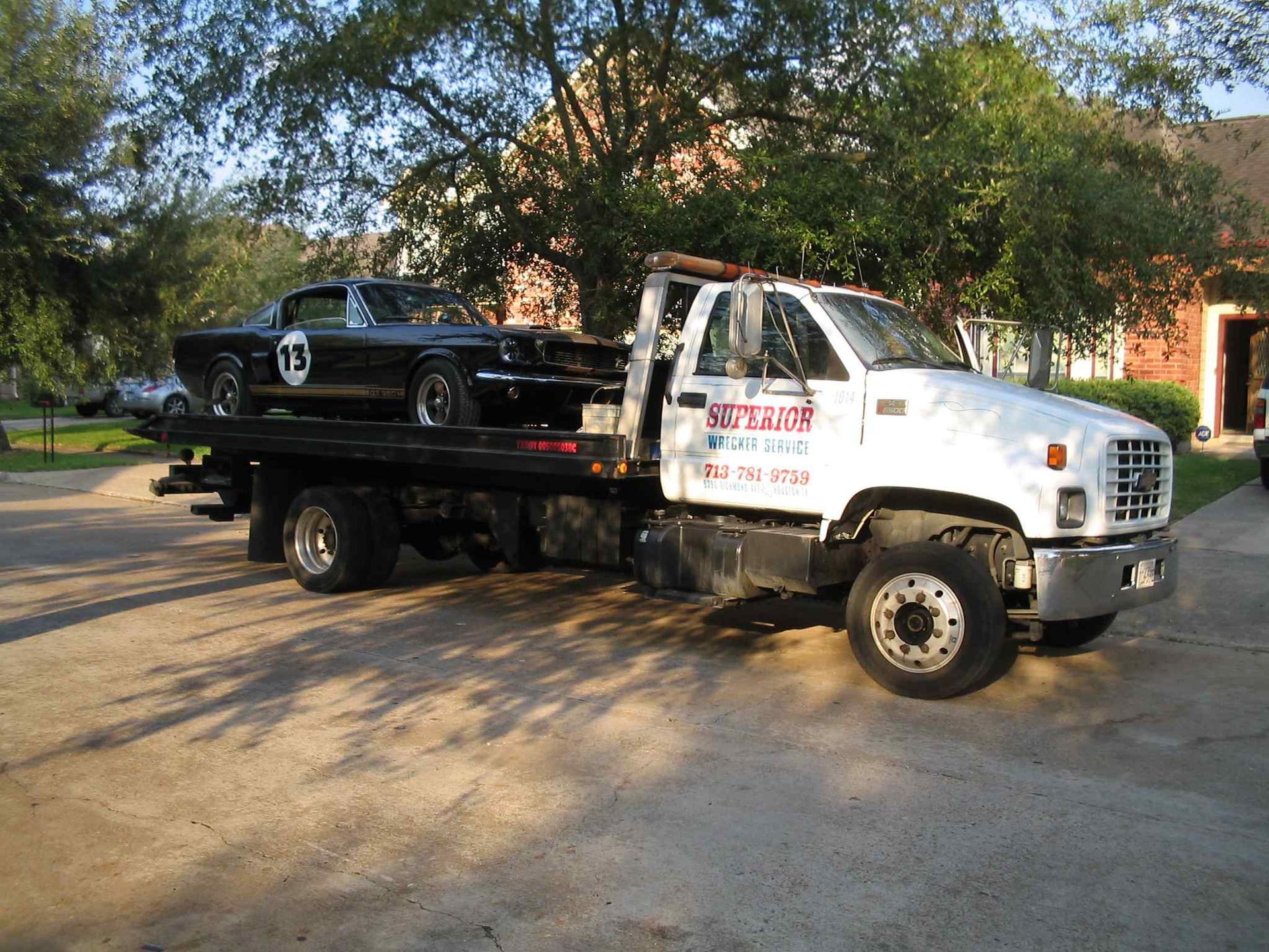 Black classic car on a white tow truck in a driveway