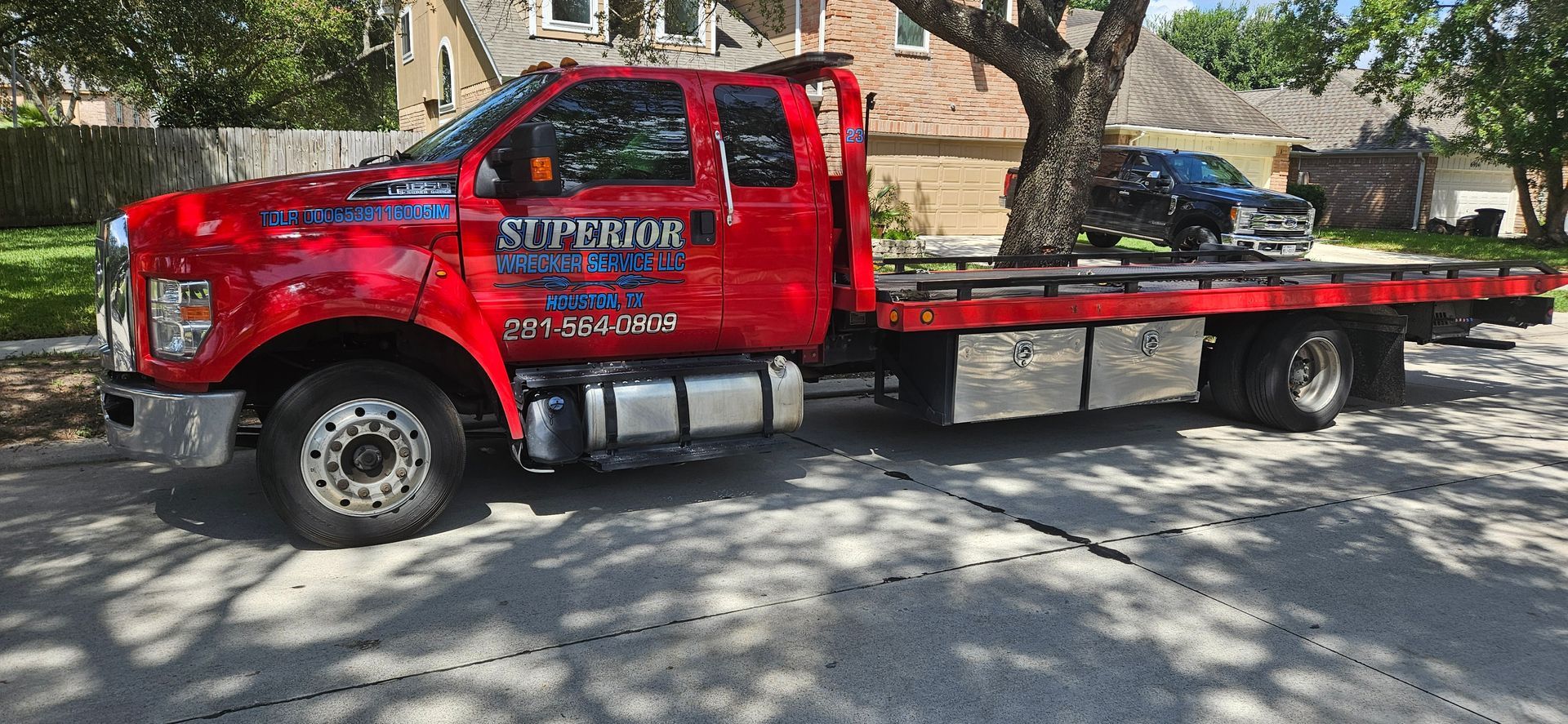 Red tow truck with a black car on the back
