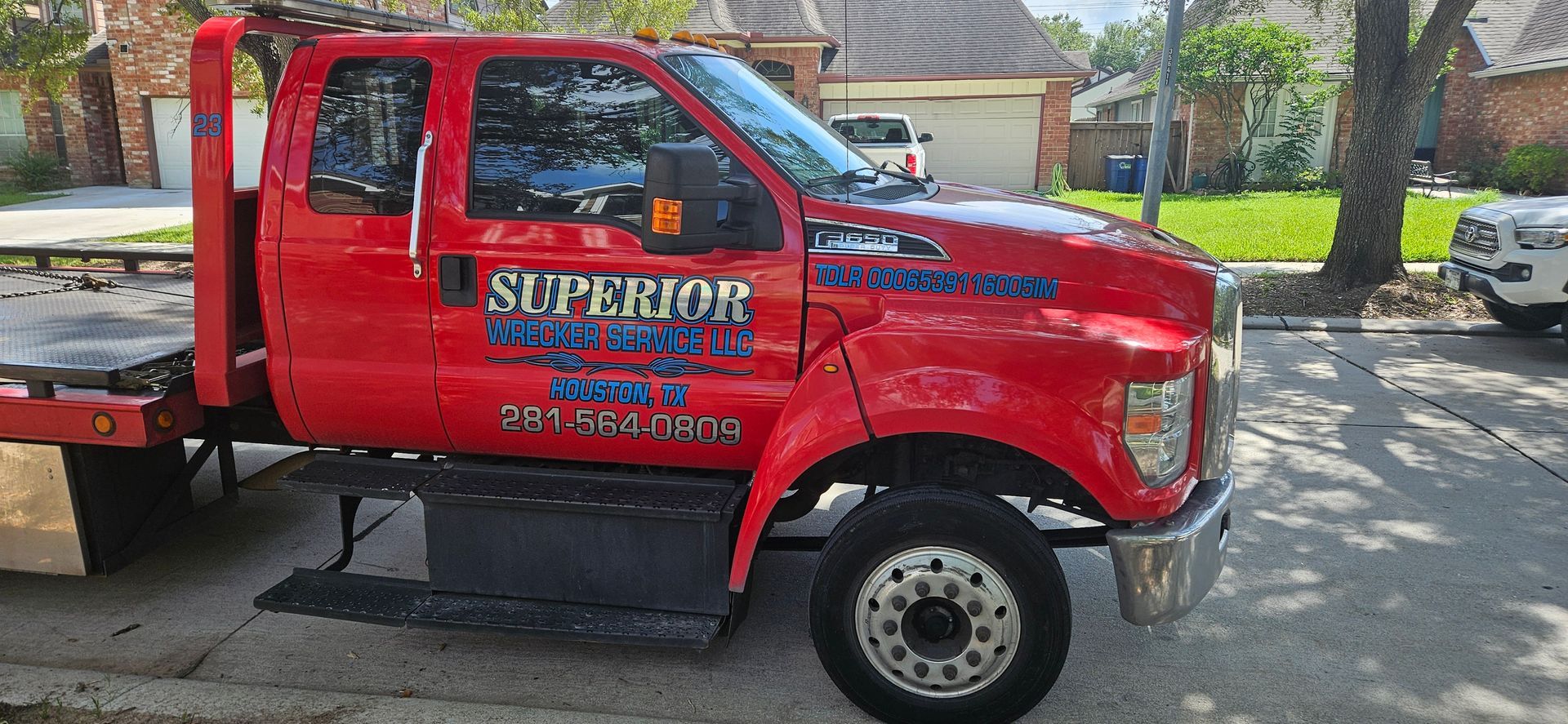 Red towing truck parked on a street in front of houses