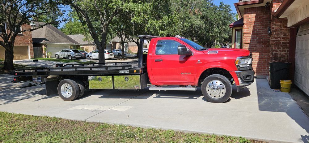 Red tow truck parked on a concrete driveway in front of a house