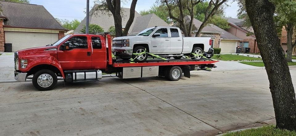Red tow truck transporting a white pickup truck on a residential street