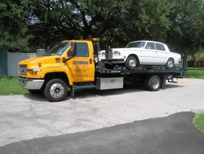 Yellow tow truck carrying a car