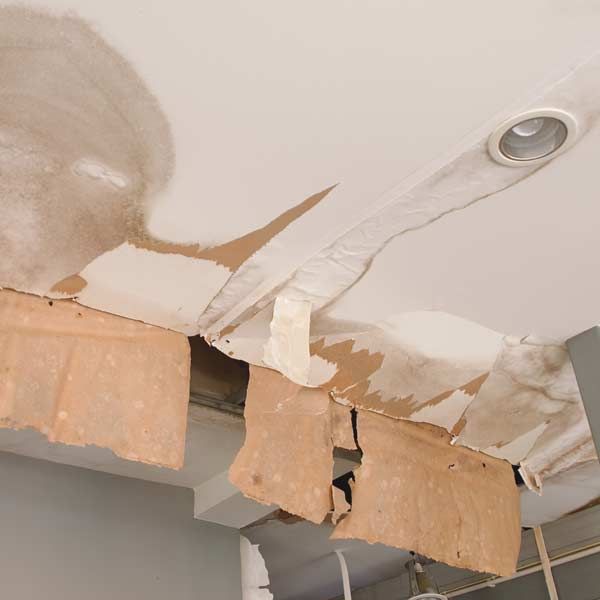 Damaged ceiling with peeling paint and water stains, likely from a leak.
