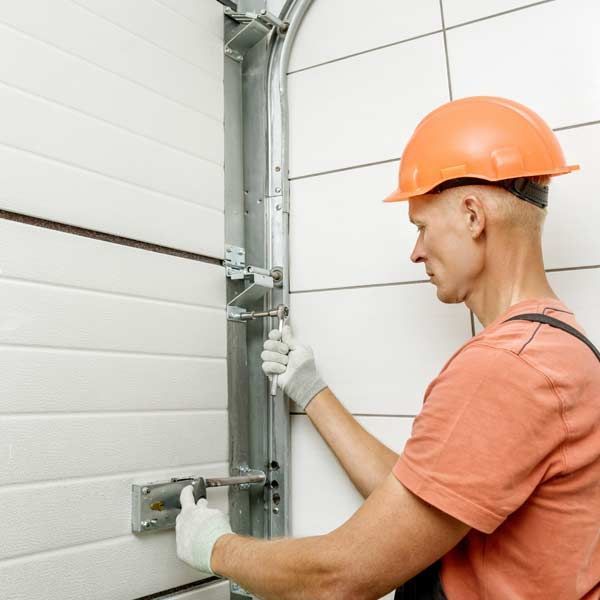 A man in an orange hard hat is fixing Garage Door Replacement