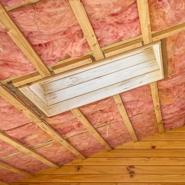 Pink insulation between wooden rafters, a recessed light fixture in the ceiling.