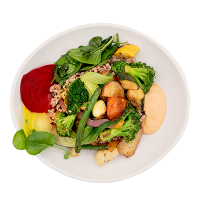 Bowl of roasted vegetables, beets, and spinach with a creamy sauce.