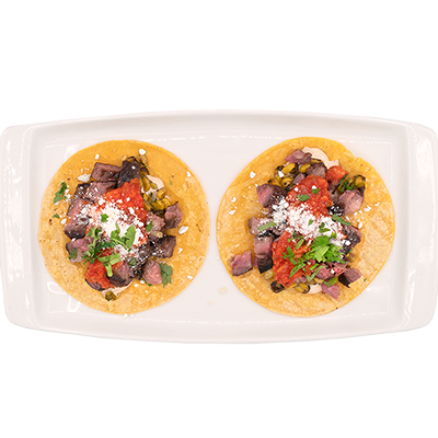Two tacos on a white platter, each with beef, salsa, and cheese on a yellow tortilla.