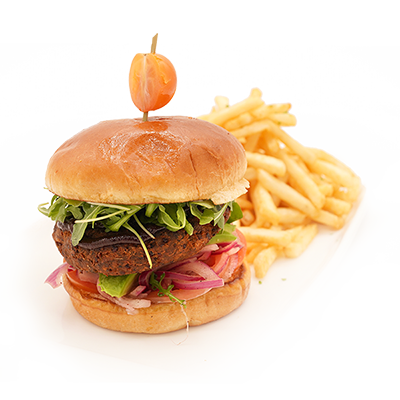 Burger on a bun with fries and a skewer on a white surface.