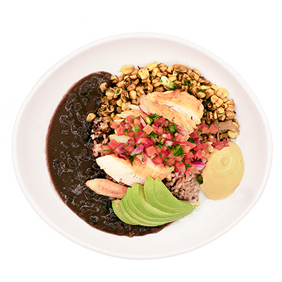 Chicken bowl with black beans, corn, avocado, pico de gallo, and sauce in a white bowl.