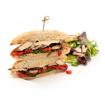 Chicken sandwich with tomatoes and greens, served with a side salad.