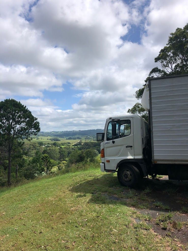 A White Truck is Parked on the Side of a Grassy Hill — Ready To Move in Mullumbimby, NSW