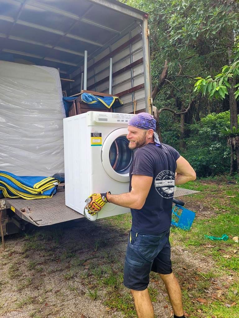 A Man is Lifting a White Washing Machine Out of a Truck — Ready To Move in Mullumbimby, NSW