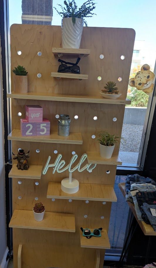 A wooden shelf with potted plants and a sign that says `` hello ''.