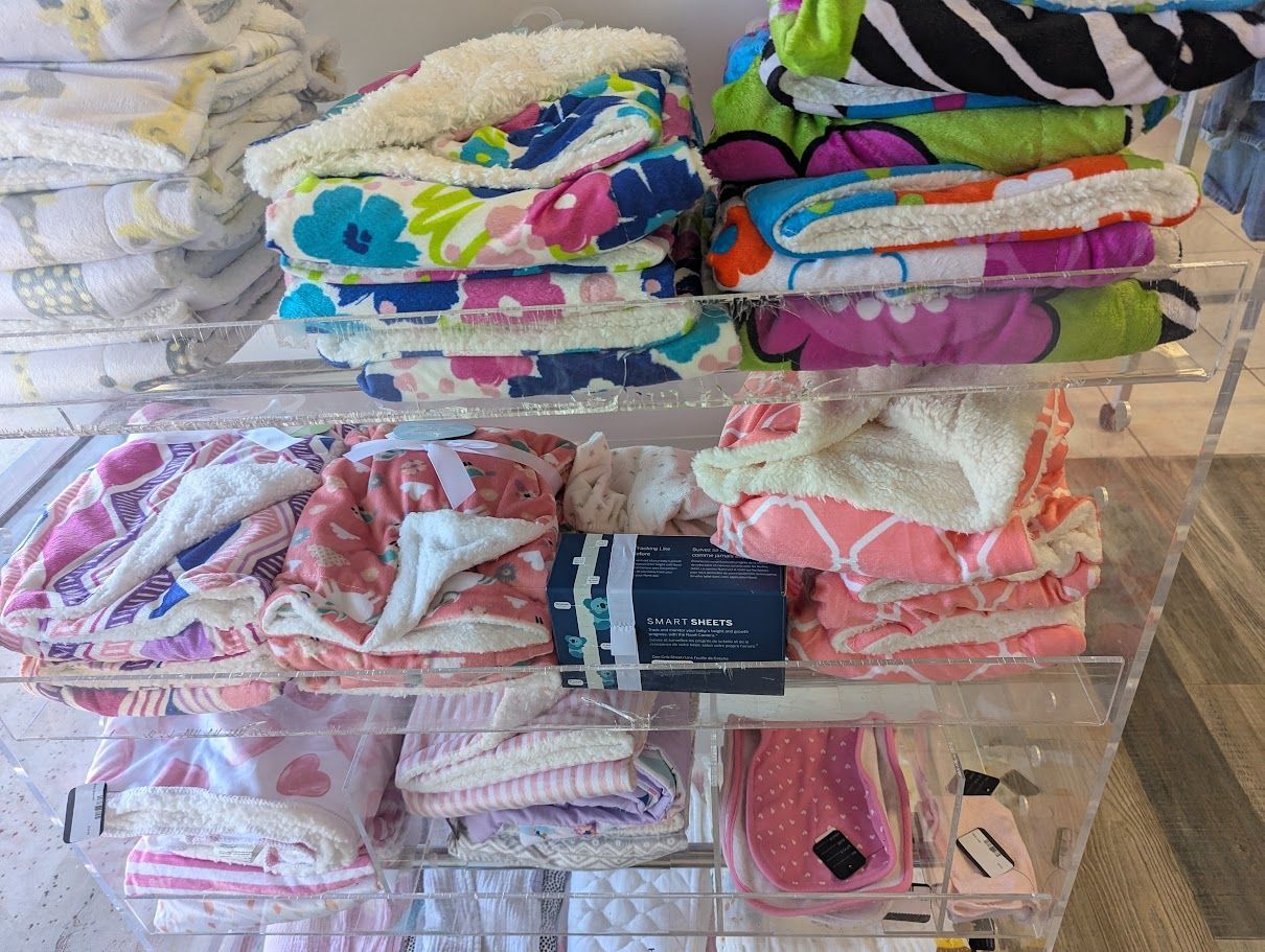 A bunch of blankets are stacked on top of each other on a shelf in a store.