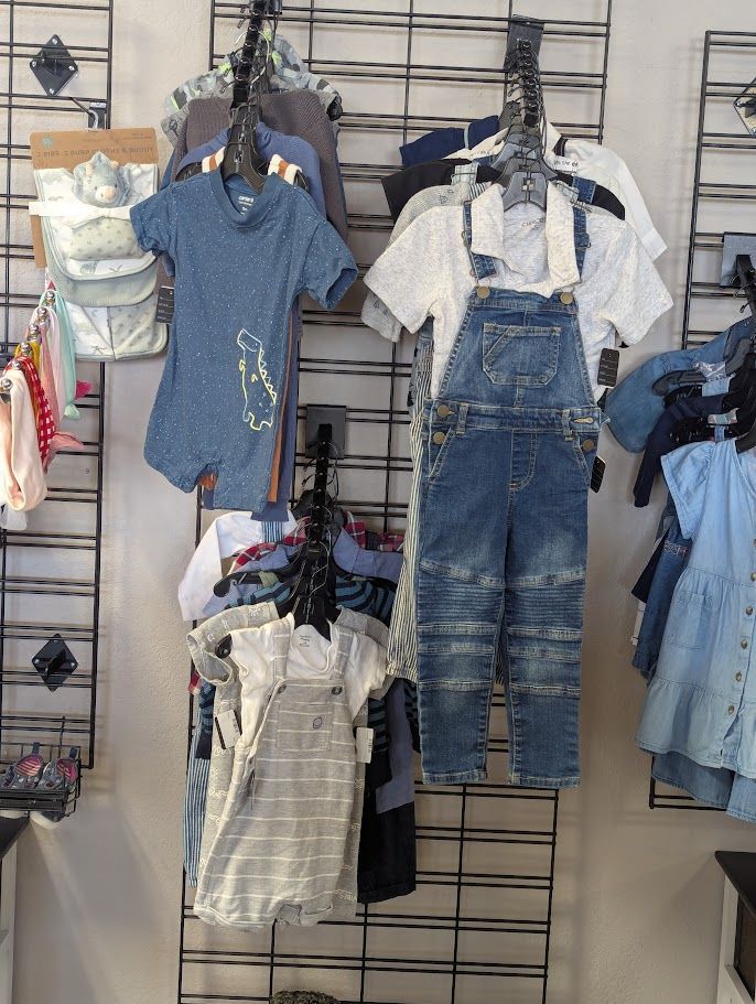 A bunch of baby clothes are hanging on a wall in a store.