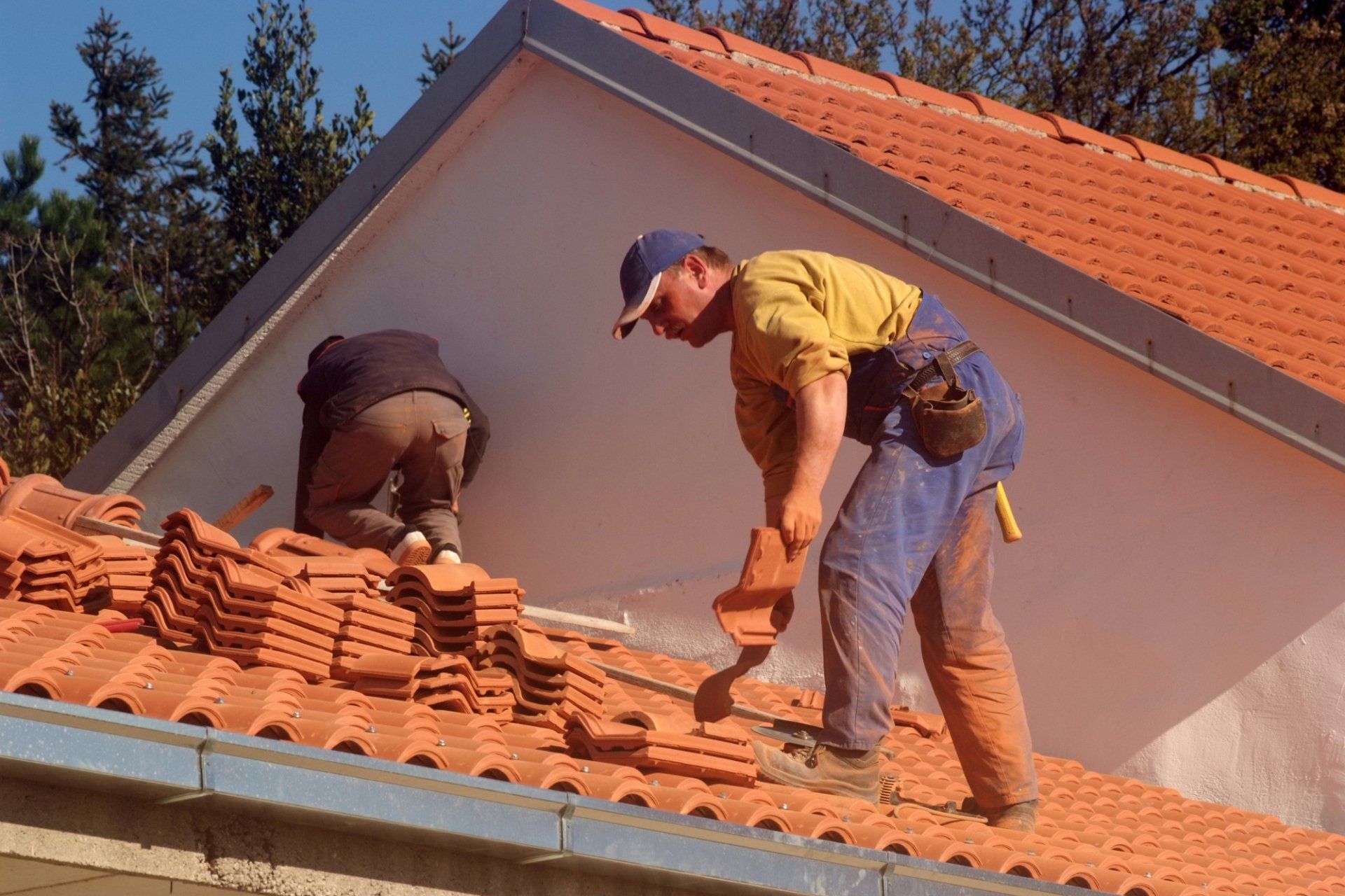 men working on roof shingles