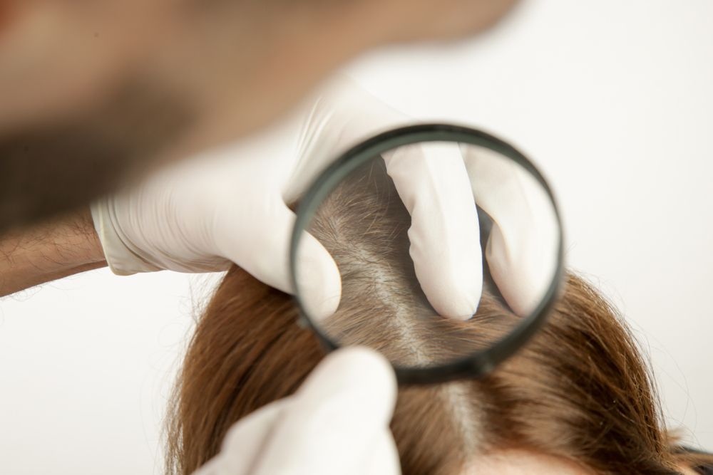 A man is examining a woman 's hair with a magnifying glass.