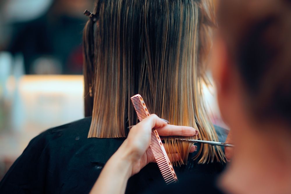 A woman is getting her hair cut by a hairdresser in a salon.